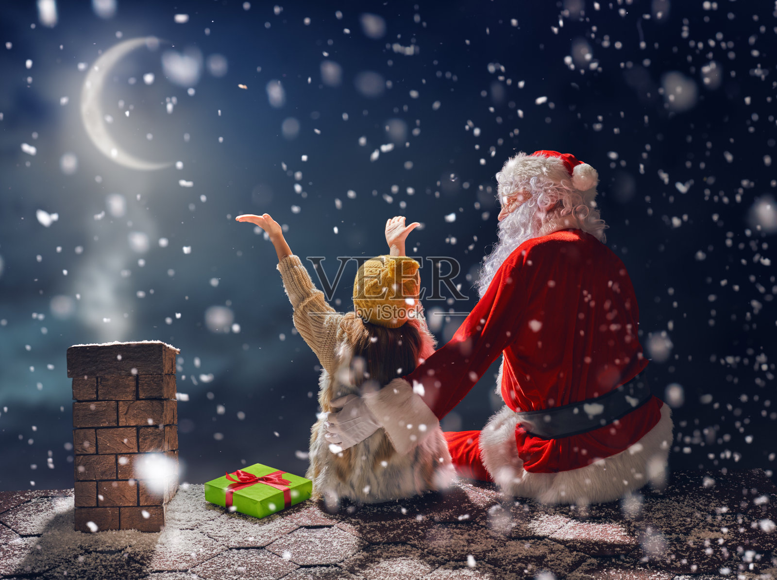 女孩和圣诞老人坐在屋顶上照片摄影图片