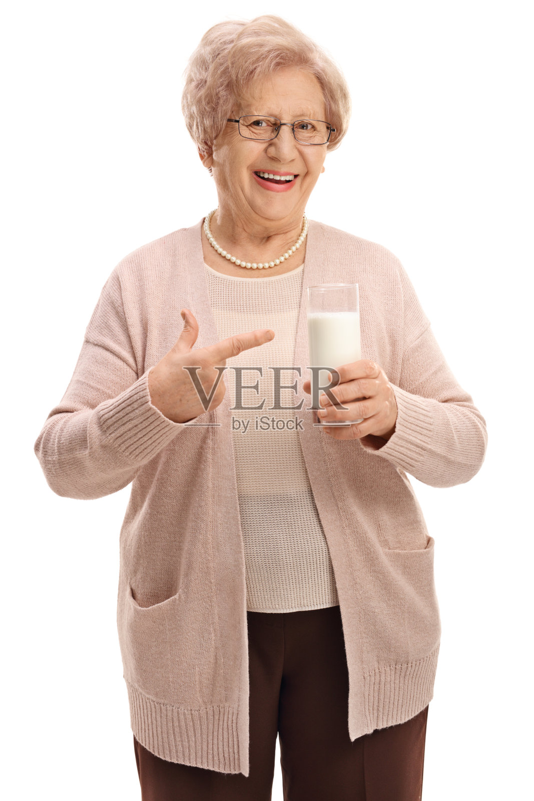 快乐的老妇人拿着一杯牛奶指着照片摄影图片