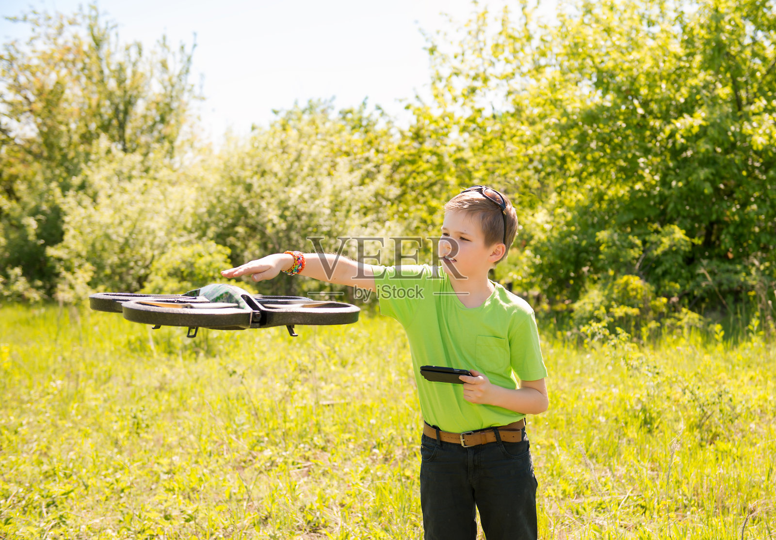 一个十几岁的男孩在用摄像头控制的智能手机玩四旋翼飞行器。照片摄影图片