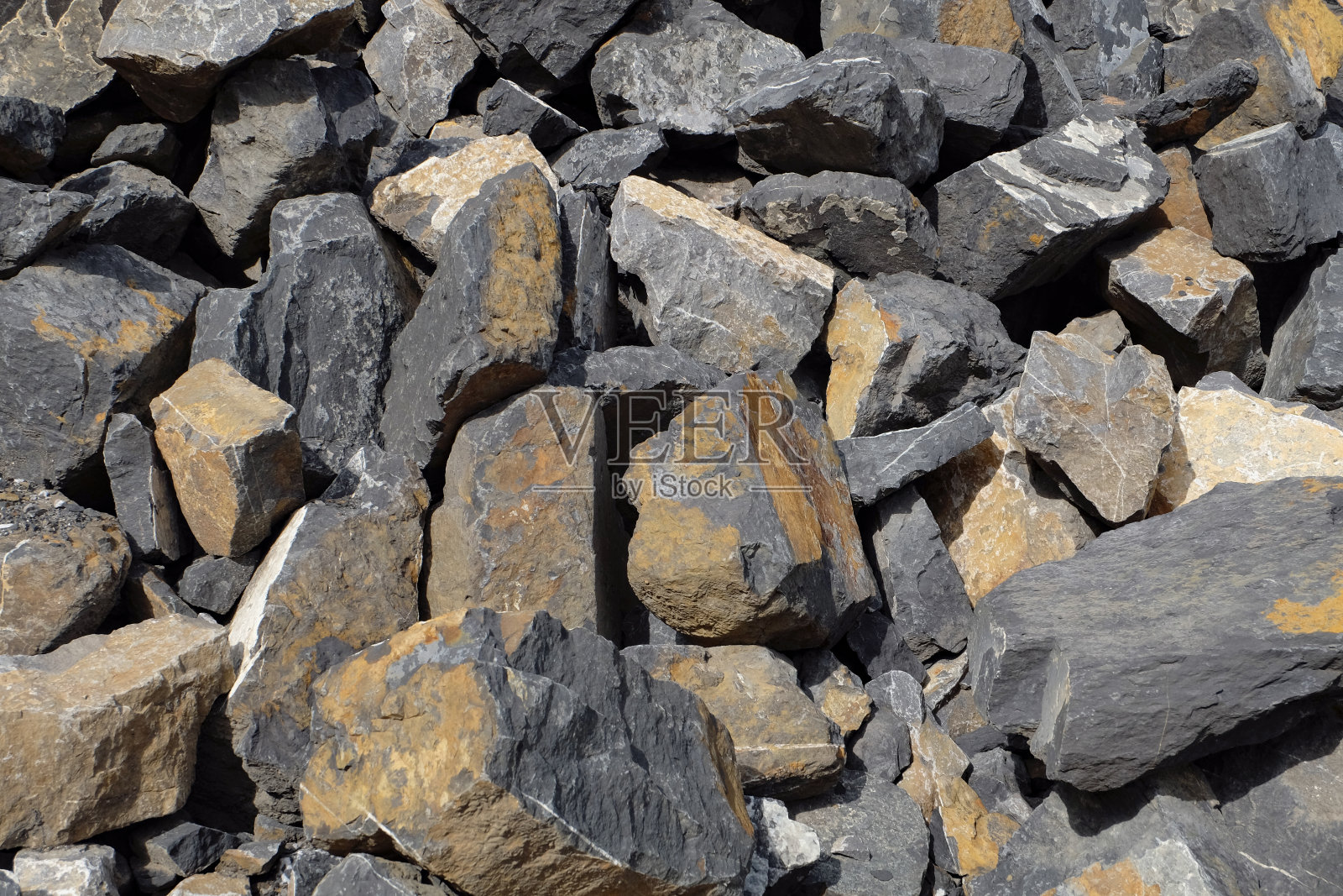 在采石场堆放的石板——形状不规则但平坦的石头，黄色和灰色，在采石场被碾碎照片摄影图片