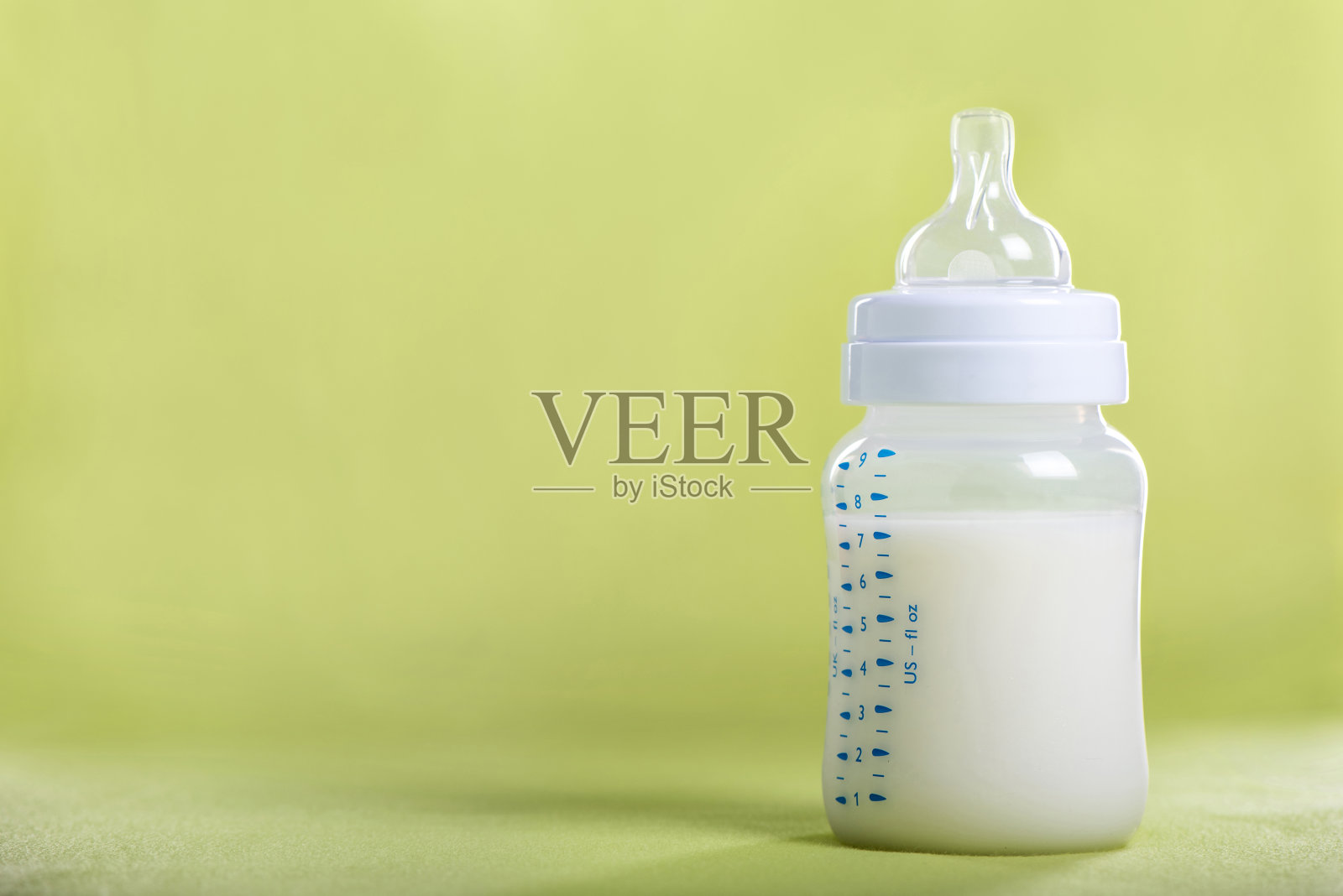 绿色床单上放着牛奶的婴儿奶瓶照片摄影图片