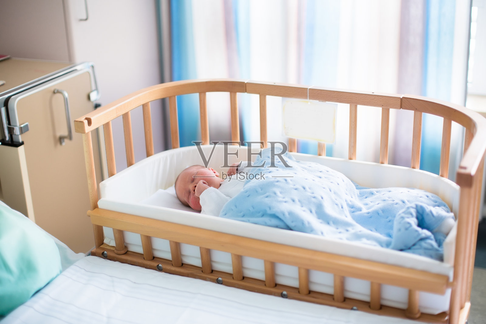 可爱的新生男婴躺在医院的婴儿床上照片摄影图片