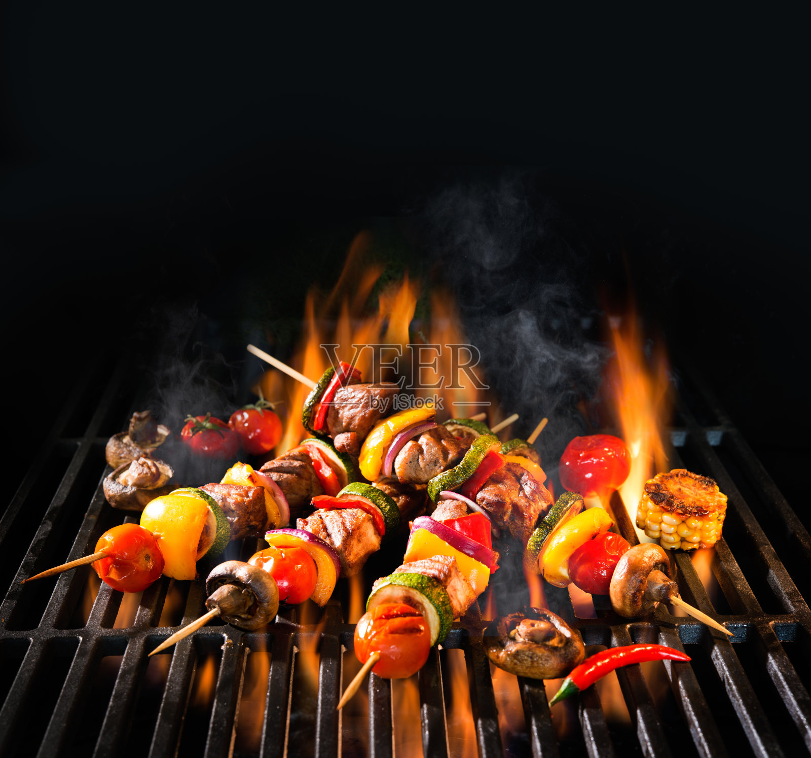烤肉串和蔬菜放在火焰烤架上照片摄影图片