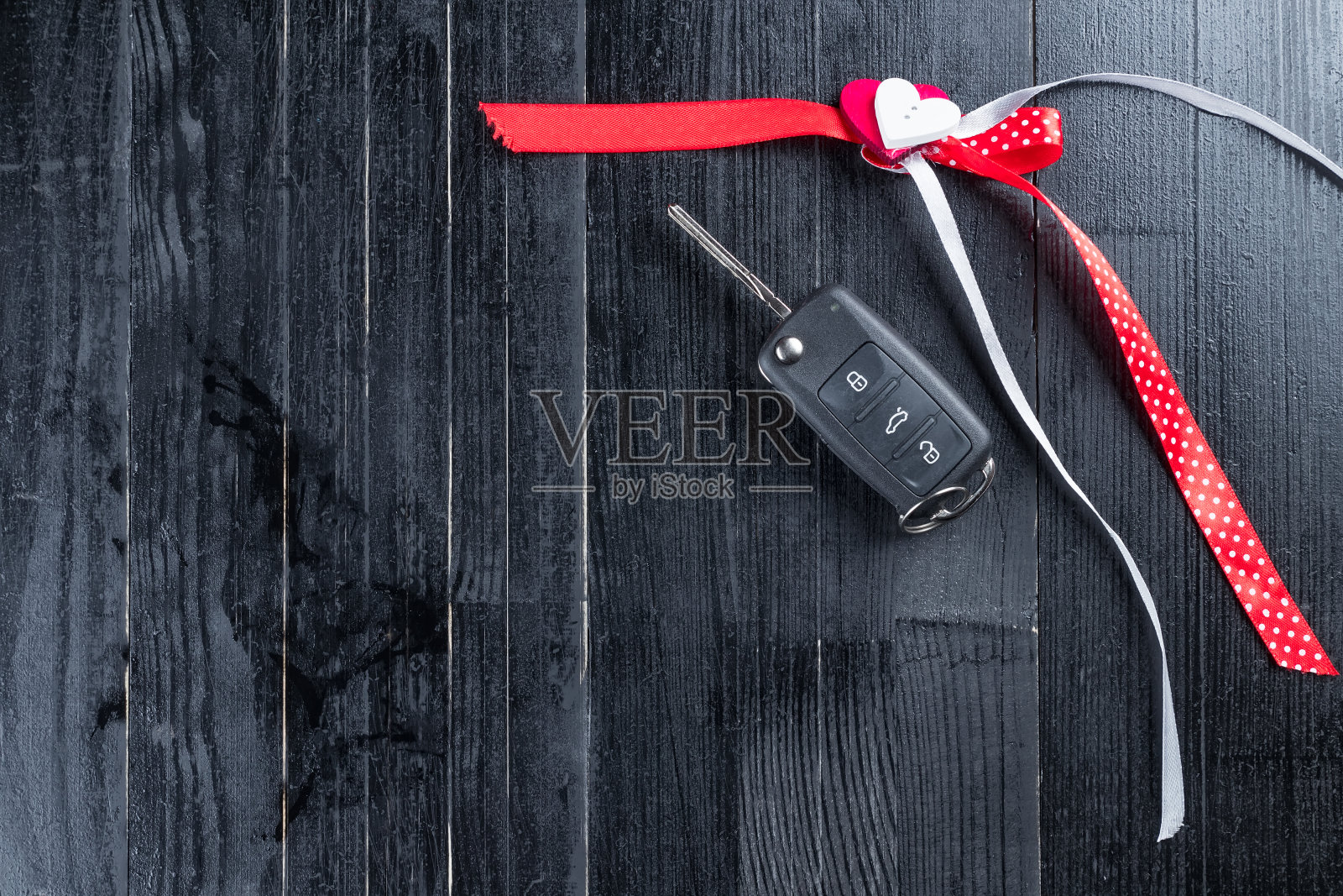 卡克钥匙与红色丝带在黑色木桌上。照片摄影图片
