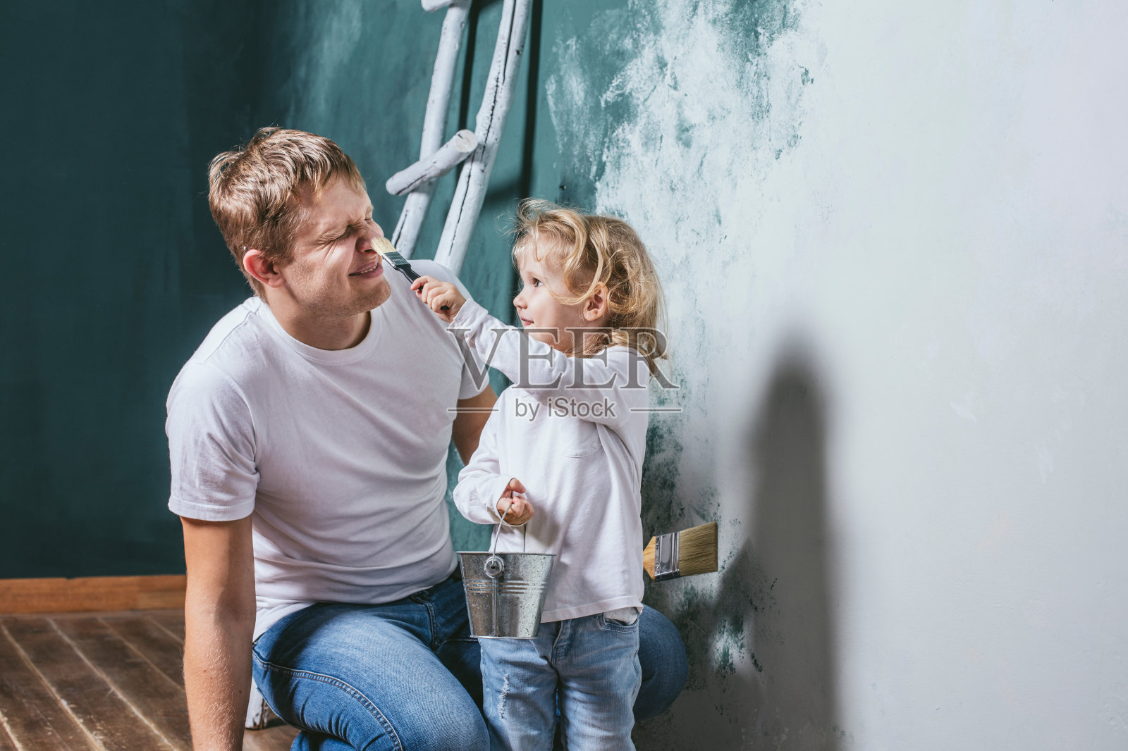 家庭，快乐的女儿和爸爸一起修房子，粉刷墙壁，照片摄影图片
