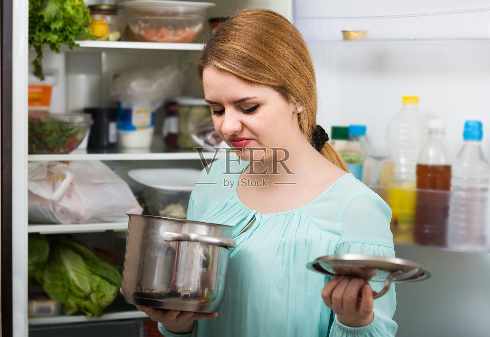 女人注意到砂锅里的食物散发出难闻的味道照片摄影图片