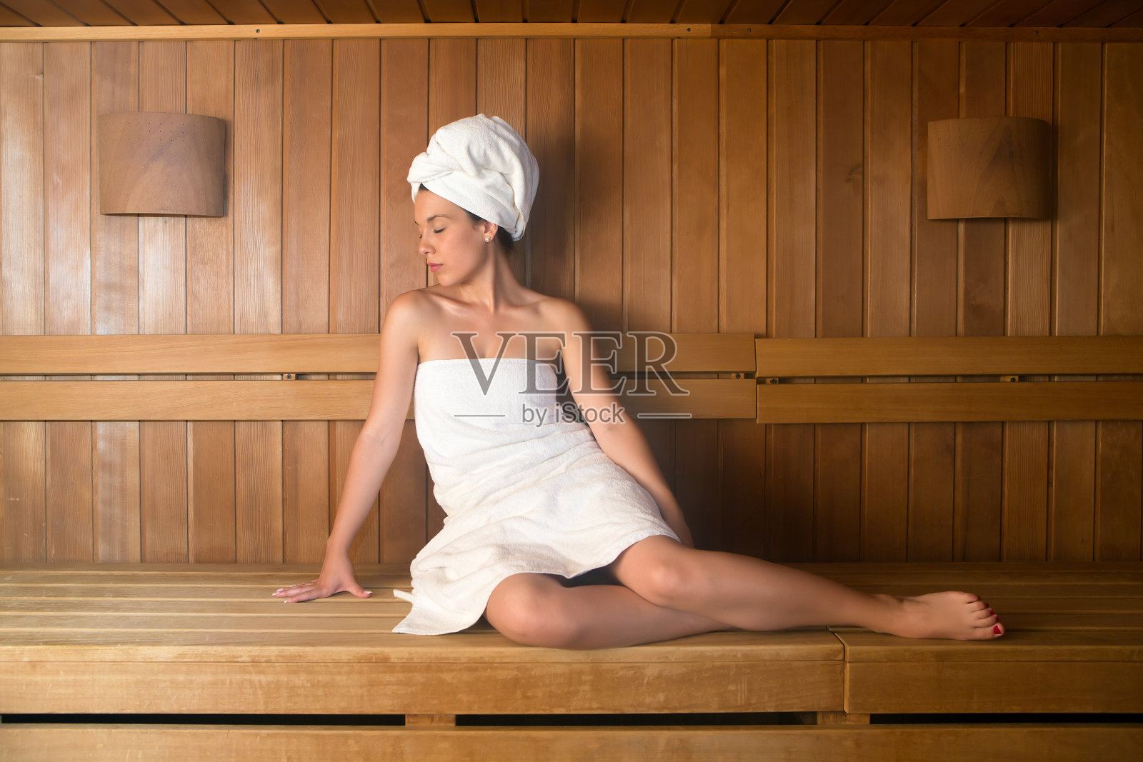 年轻女子在浴巾放松在长椅桑拿照片摄影图片