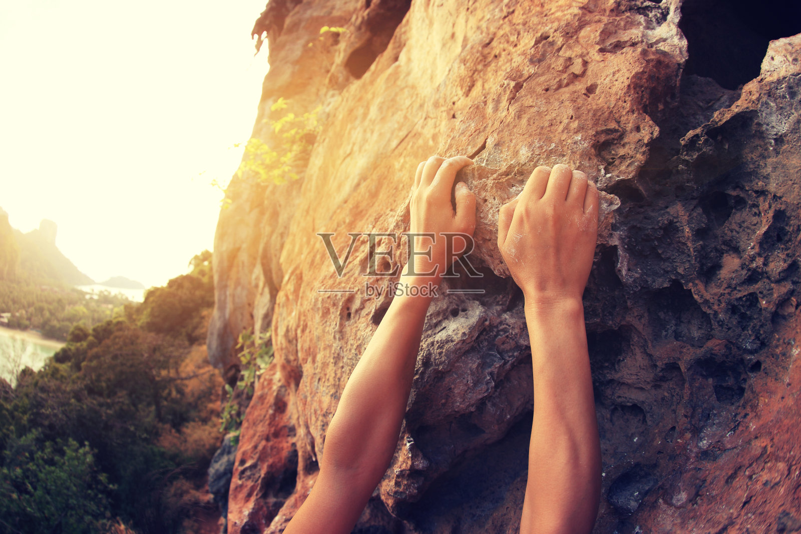 攀岩者手攀岩海边的山崖岩石照片摄影图片