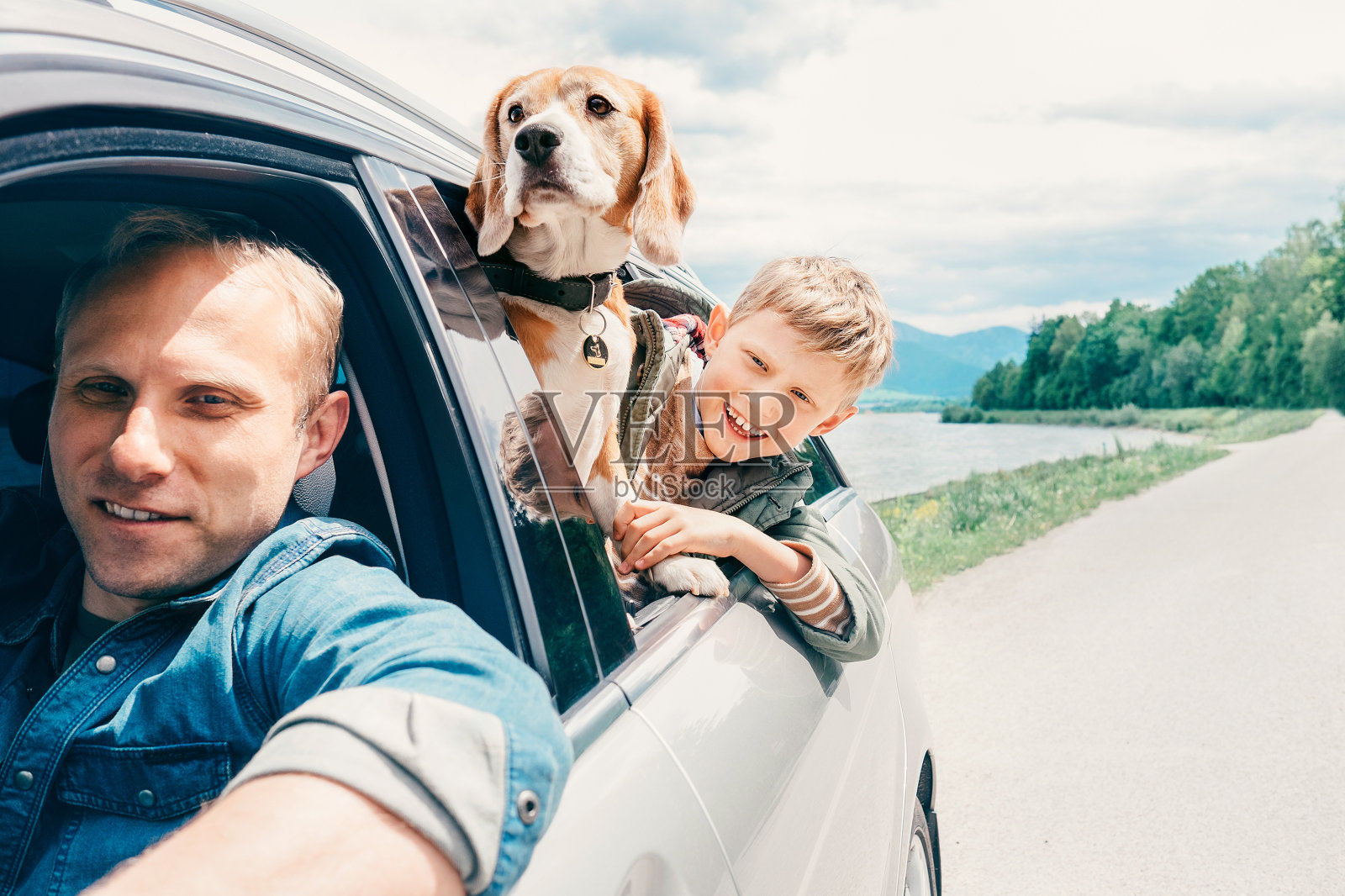 父亲带着儿子和狗从车窗往外看照片摄影图片
