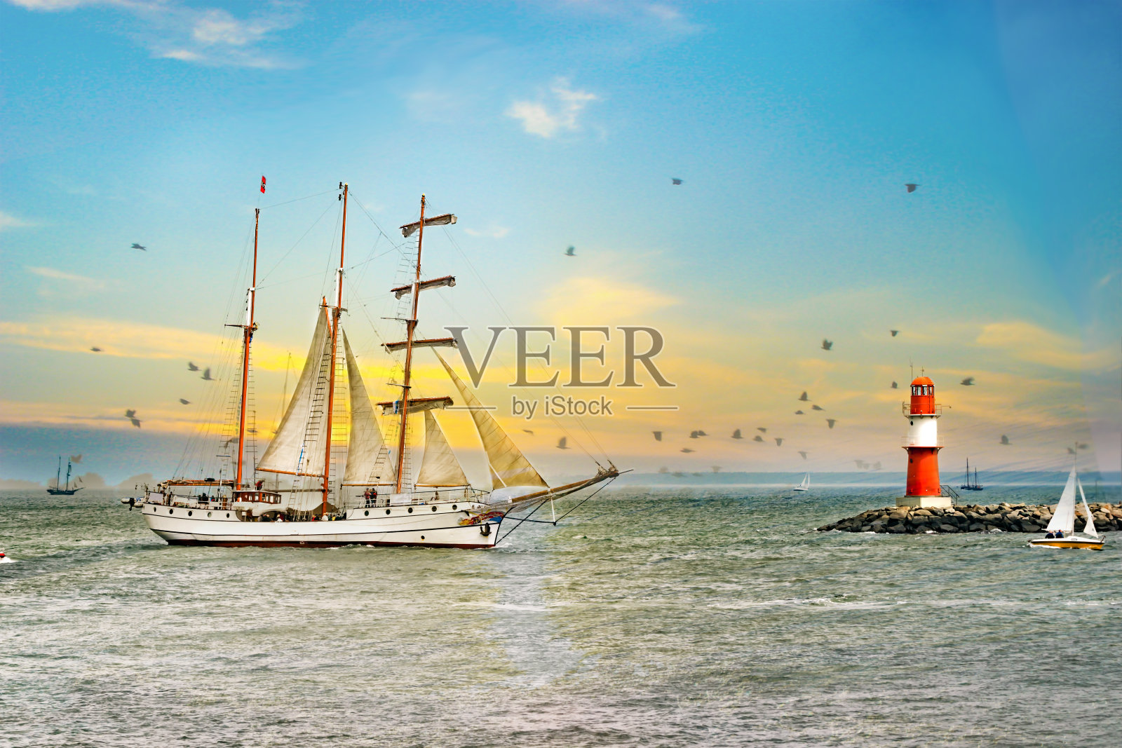 日落时分海上的帆船。灯塔和鸟。照片摄影图片