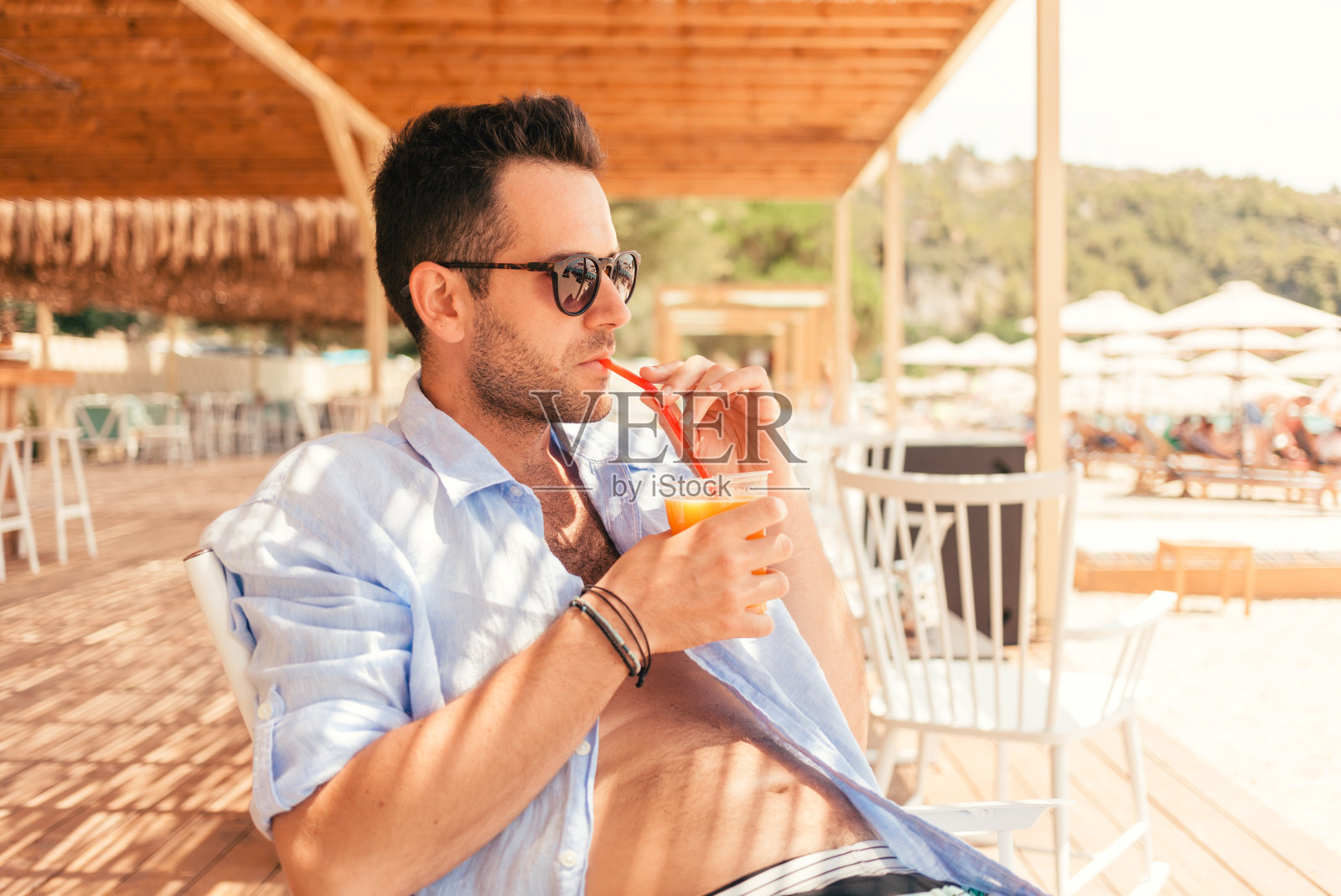 帅气的潮男喝着美味的鸡尾酒，夏天旅行照片摄影图片