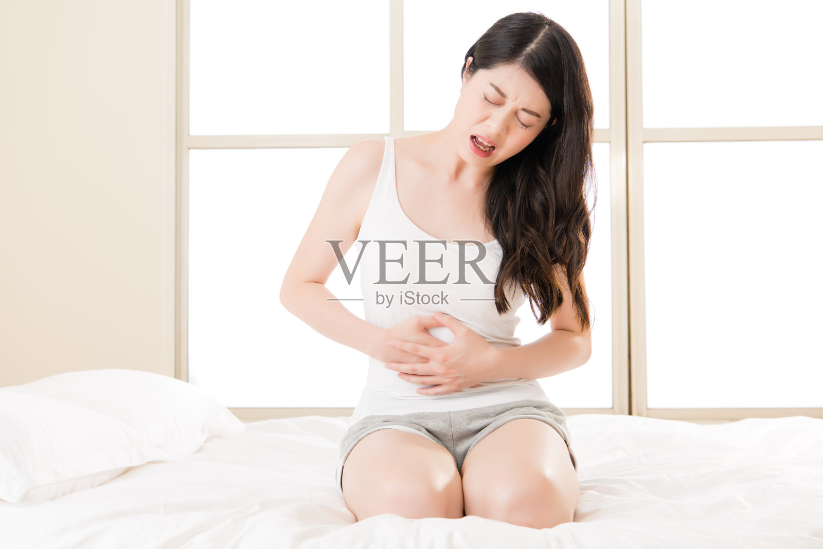 美丽的亚洲女人在床上遭受胃痛照片摄影图片