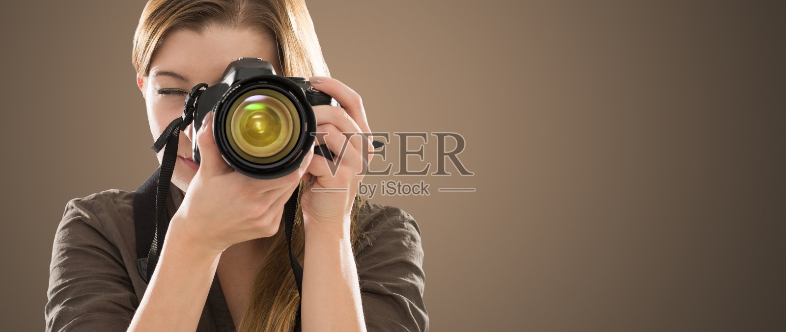 一个摄影师用相机遮住她的脸的肖像。照片摄影图片