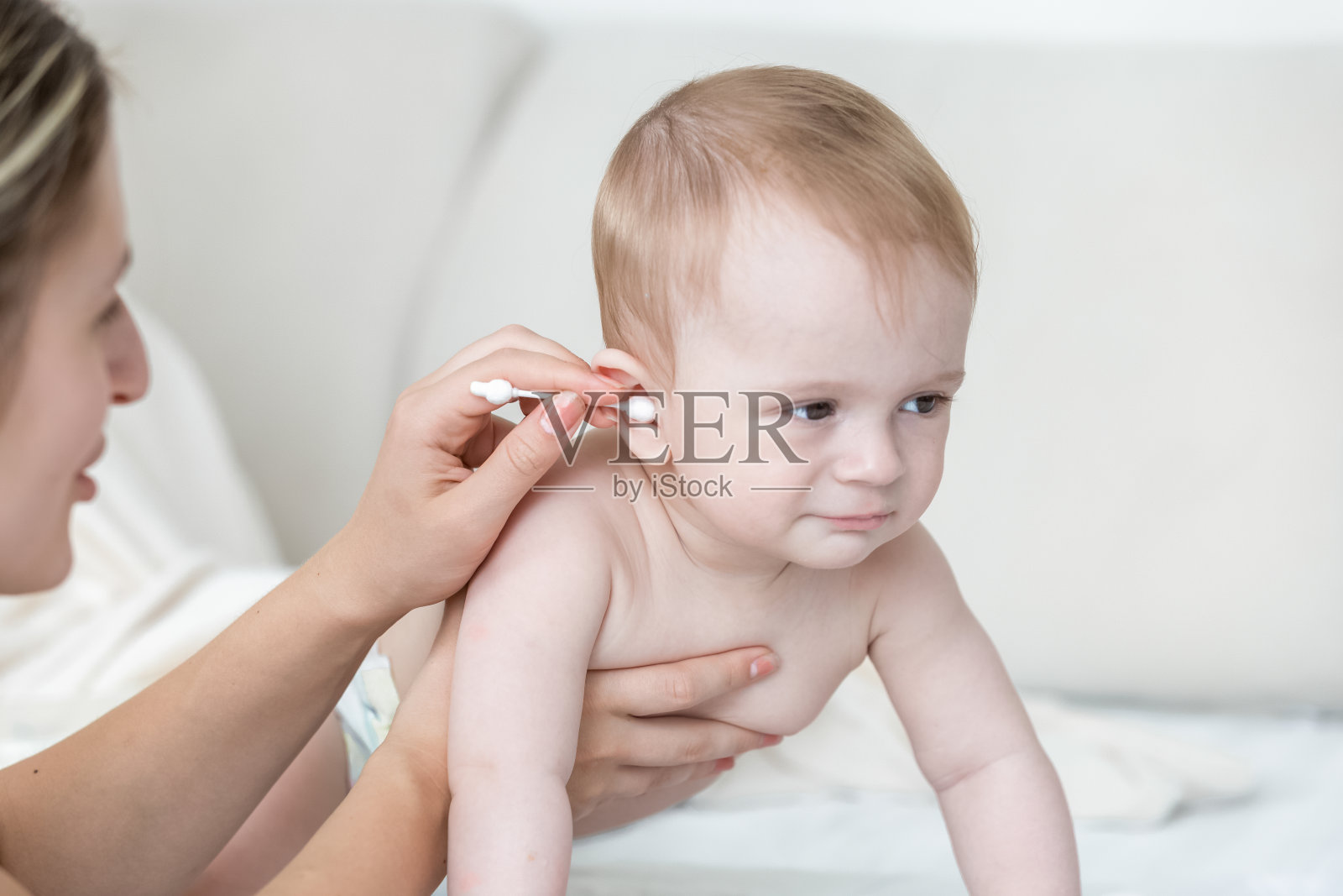 年轻的母亲在宝宝洗澡后用棉签擦拭耳朵照片摄影图片