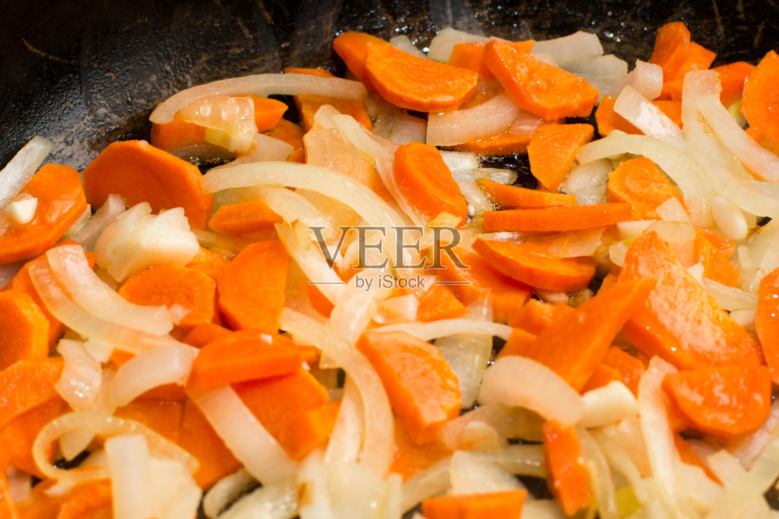 把洋葱和胡萝卜放进锅里照片摄影图片
