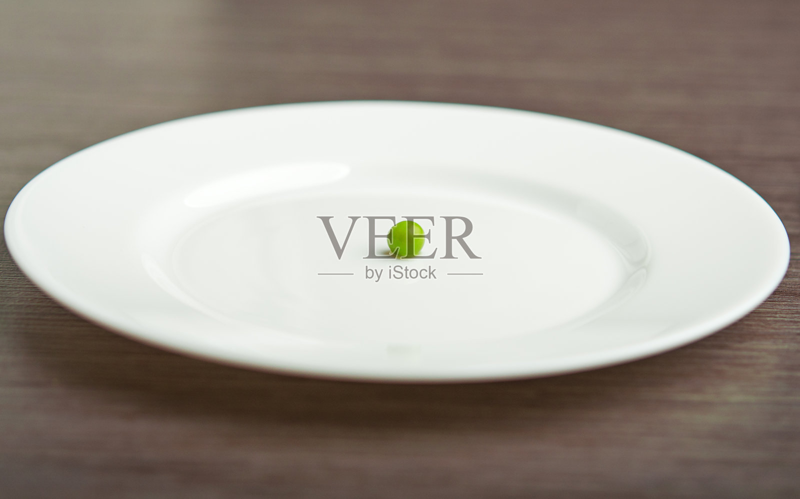 饮食的概念。白盘子里的一颗豌豆照片摄影图片
