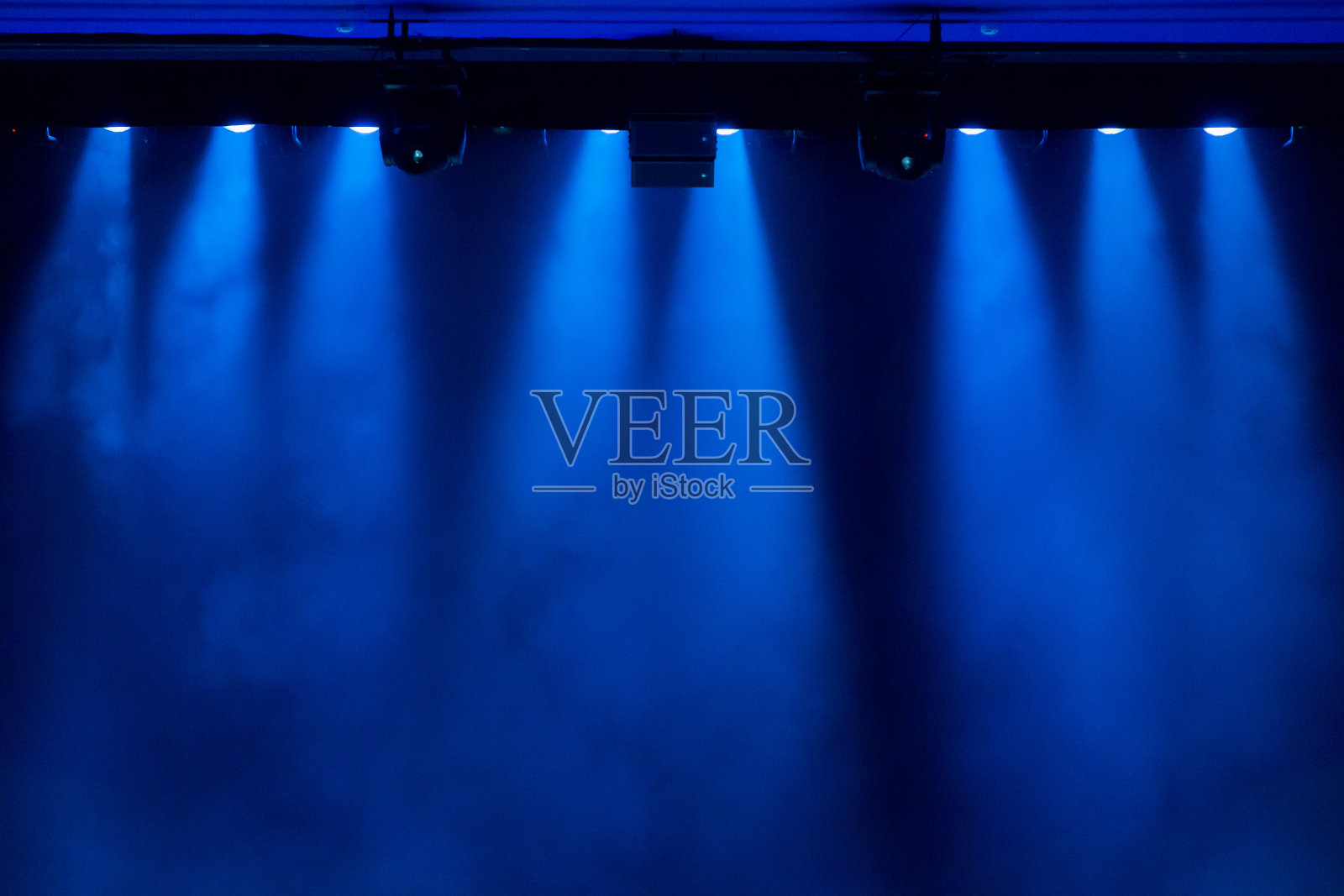 在演出期间，聚光灯发出的蓝光透过剧院里的烟雾。照明设备。照片摄影图片