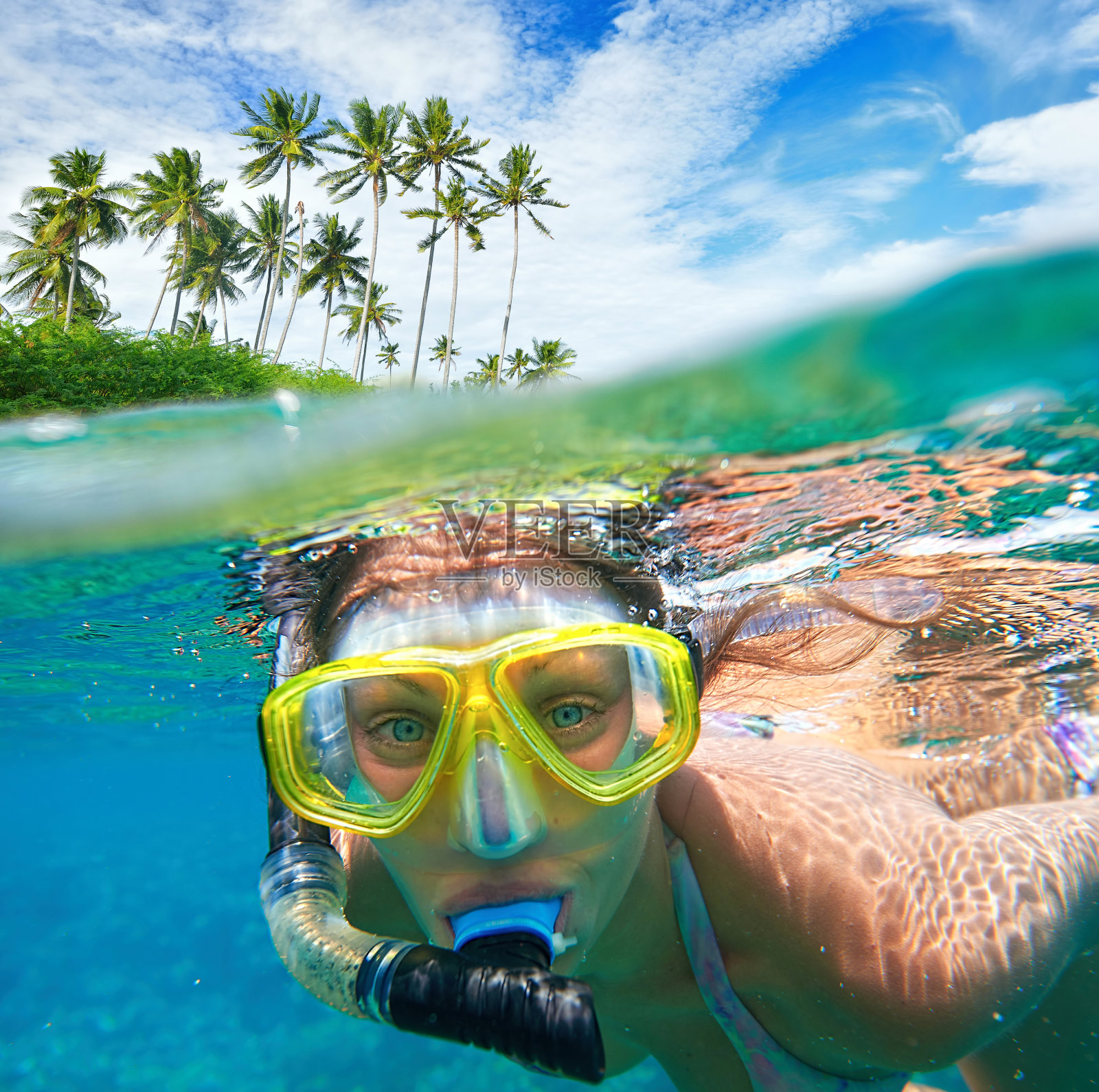戴着面罩的女人在清澈的水中潜水。照片摄影图片
