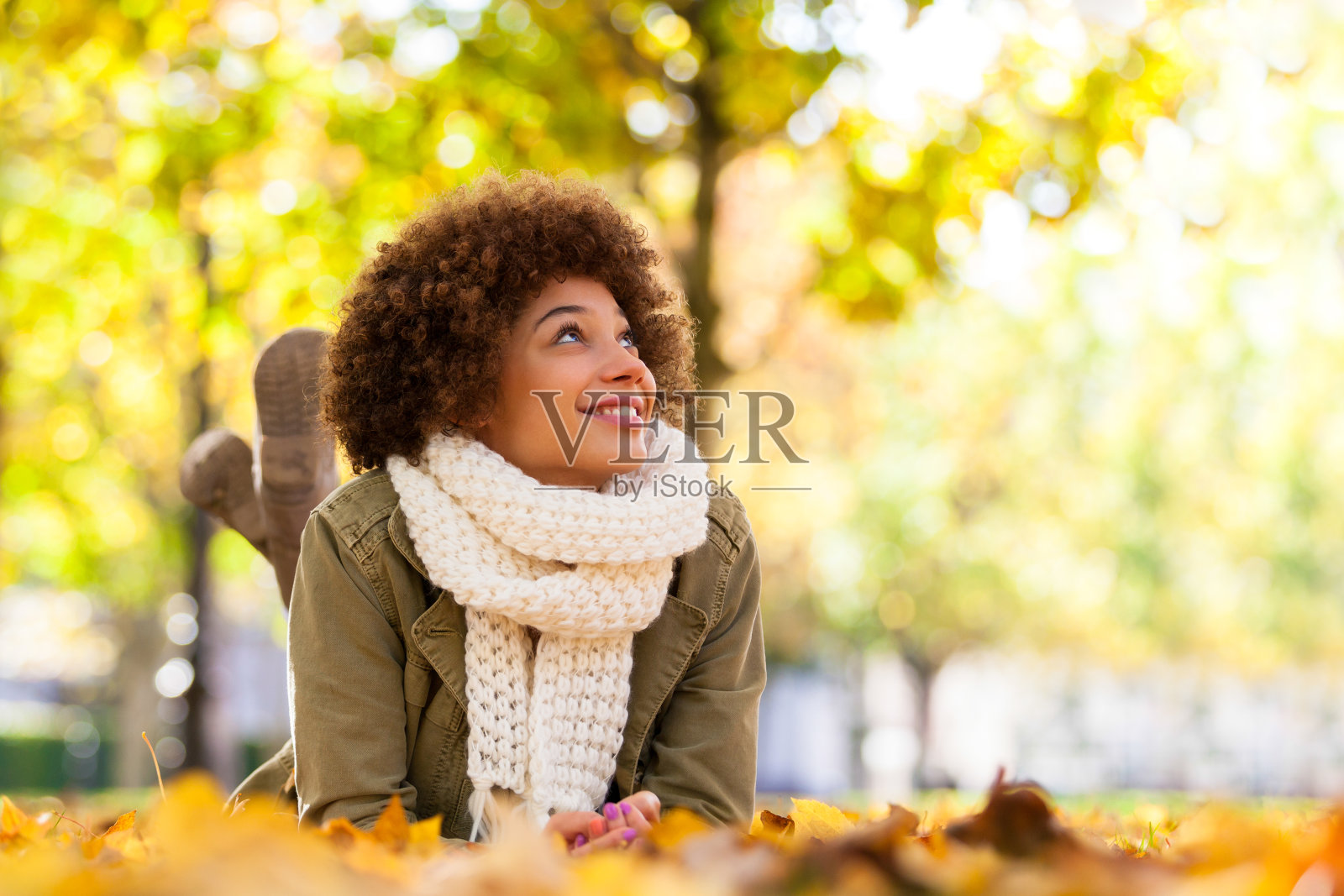 年轻微笑的非裔美国妇女躺在落叶上照片摄影图片
