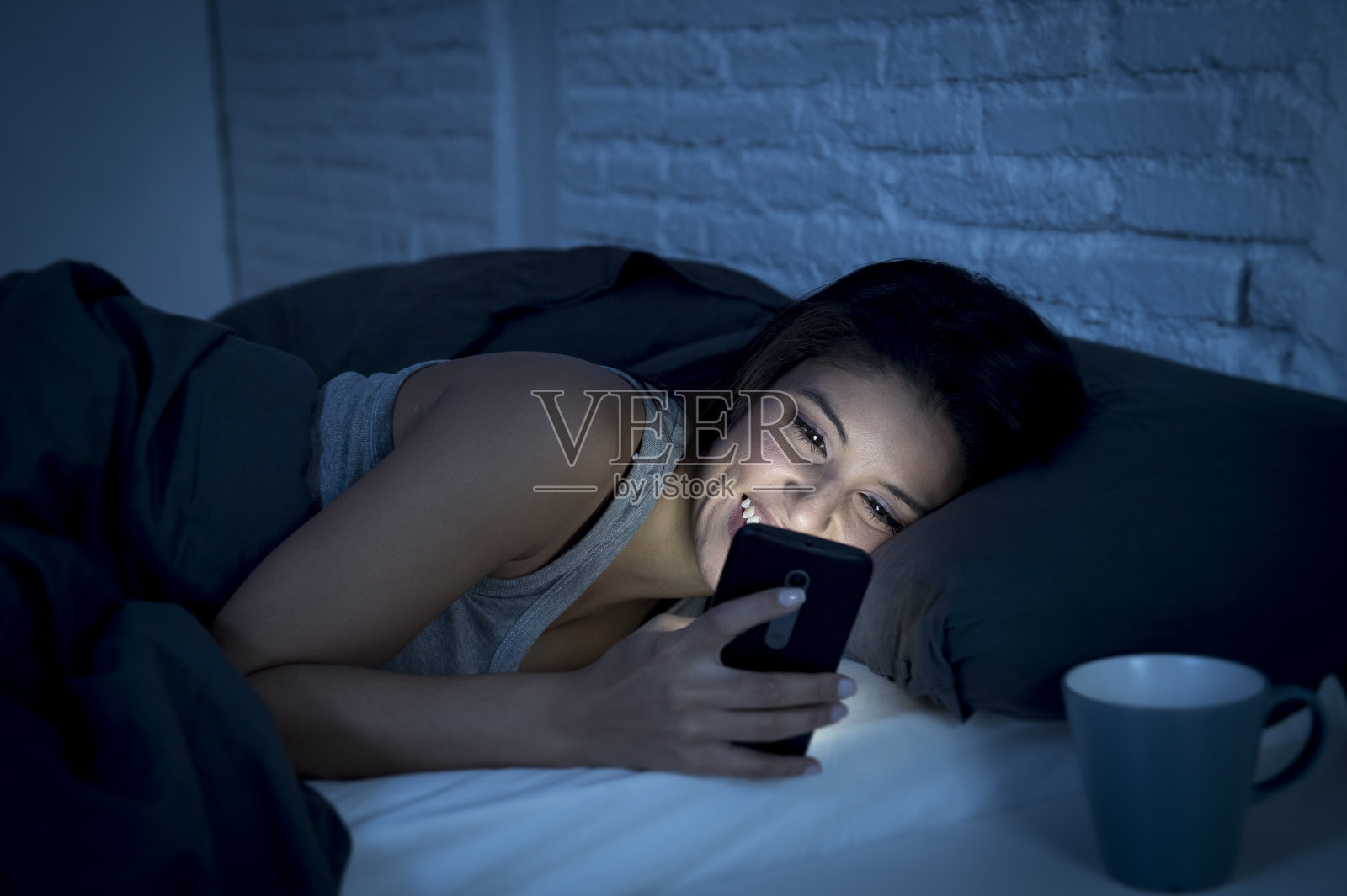 女孩深夜在床上用手机开心放松照片摄影图片