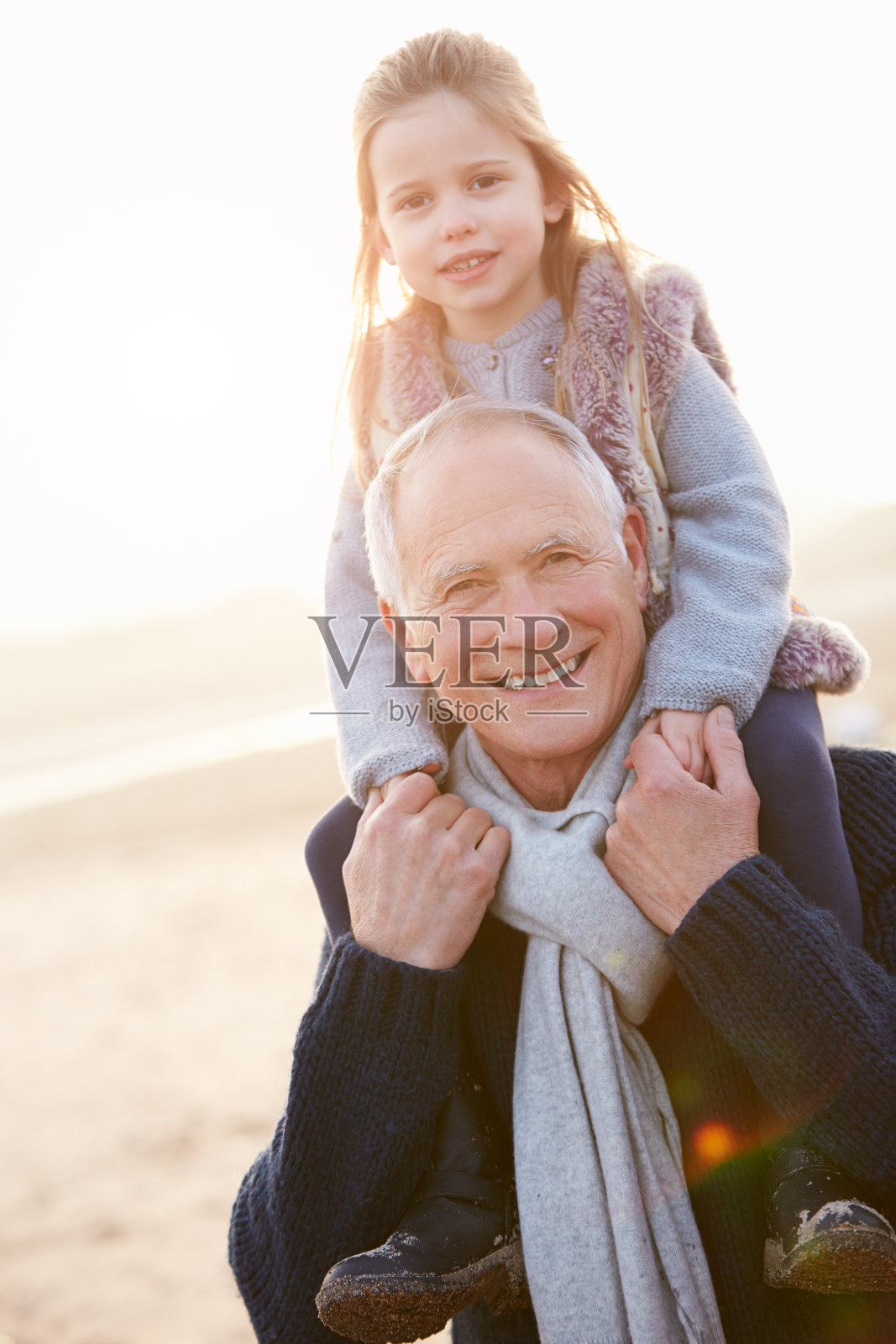 爷爷和孙女在冬天的海滩上散步照片摄影图片