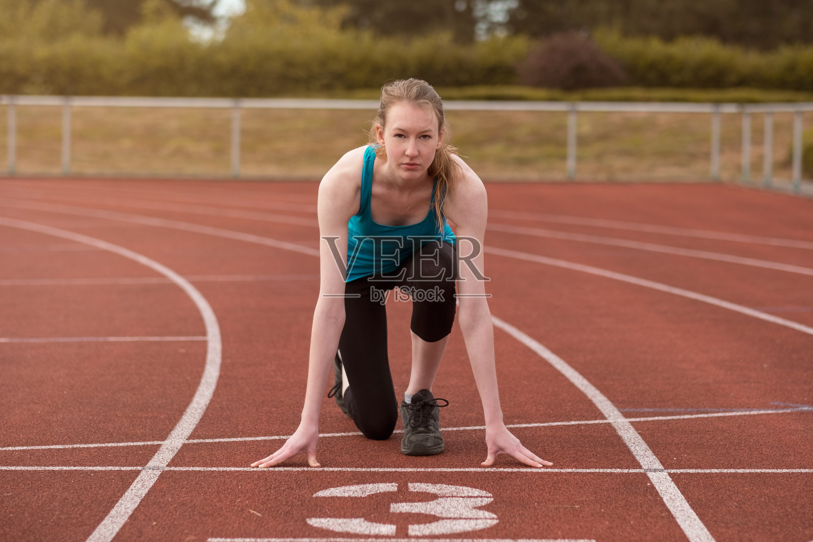 年轻女子短跑运动员，起跑姿势照片摄影图片