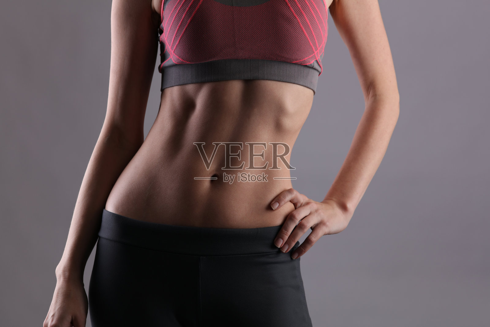 运动,健康的女人。女性腹部肌肉完美的灰色背景。节食，健身，积极的生活方式概念，复制空间照片摄影图片
