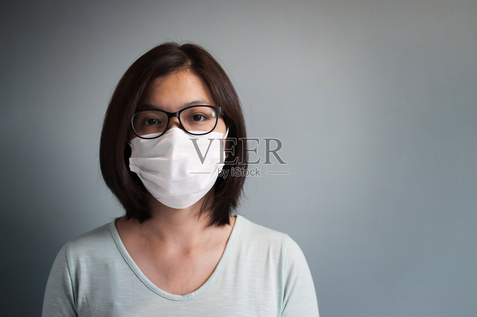 亚洲眼镜妇女戴医疗口罩与复制空间。照片摄影图片