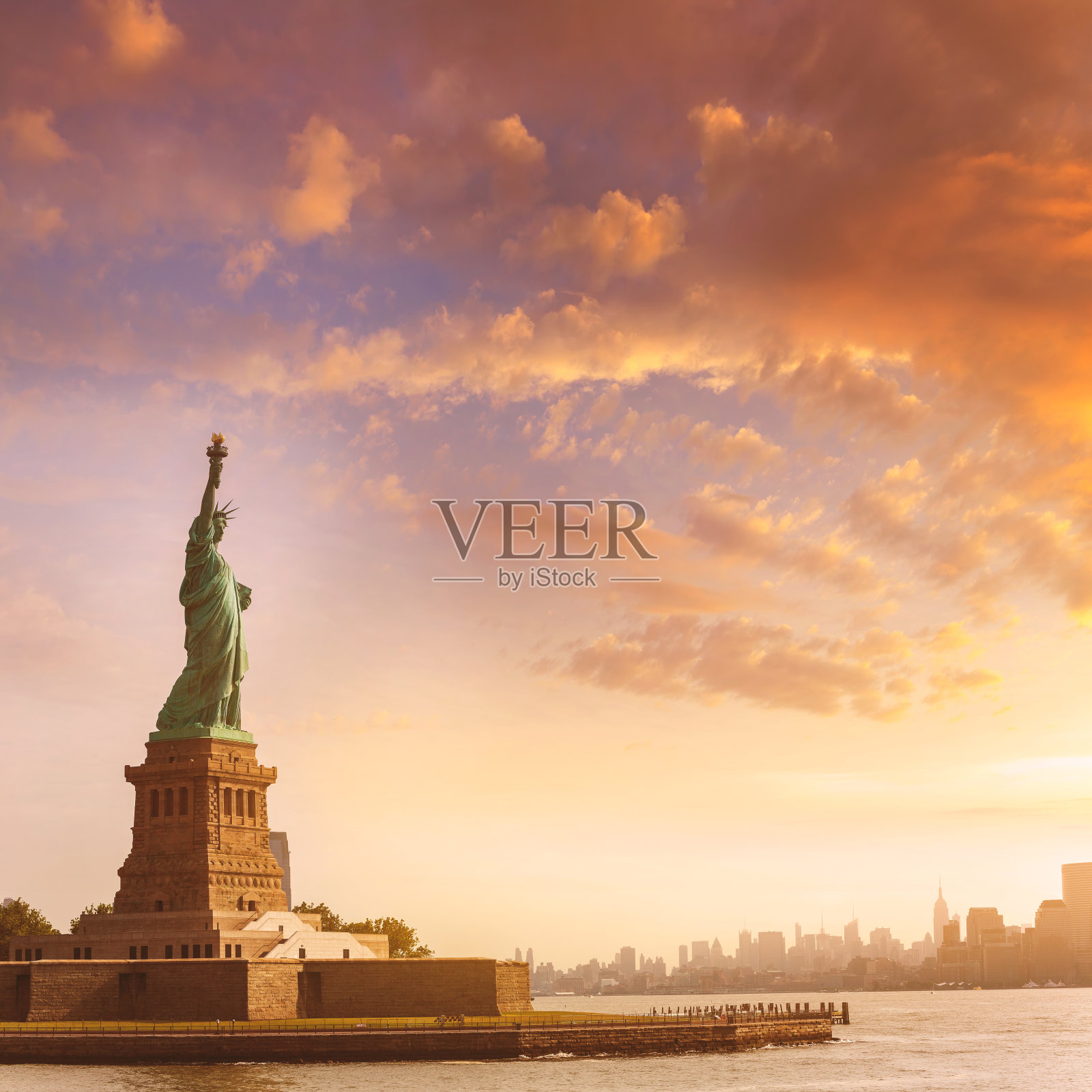 日出时纽约为背景的自由女神像照片摄影图片