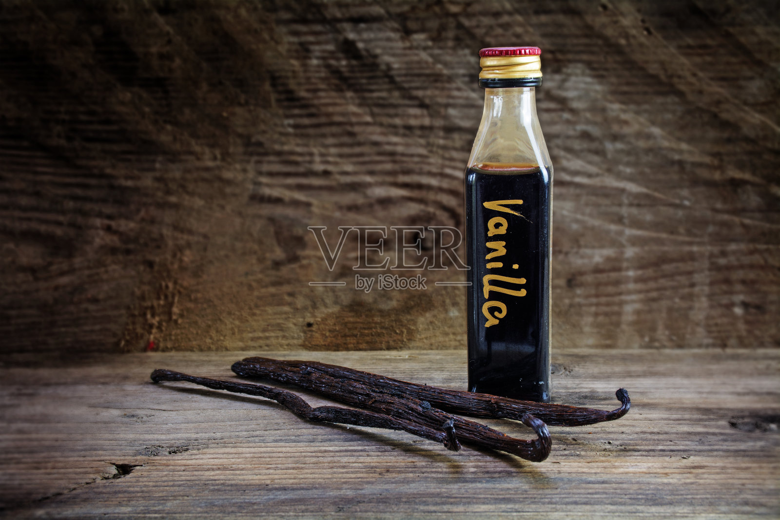瓶中香草精和豆荚放在乡村木材上照片摄影图片