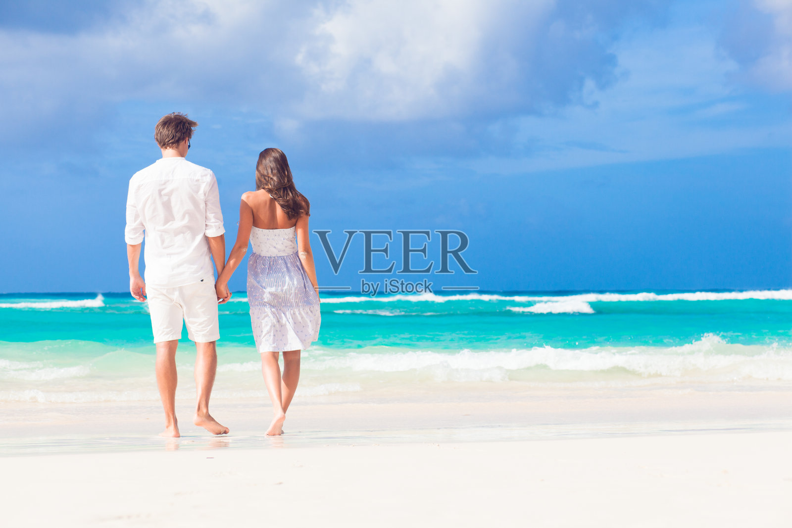 年轻幸福的夫妇穿着白色衣服在热带海滩。度蜜月照片摄影图片