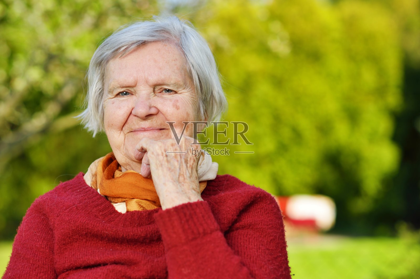 老女人微笑着，在花园里做梦。照片摄影图片