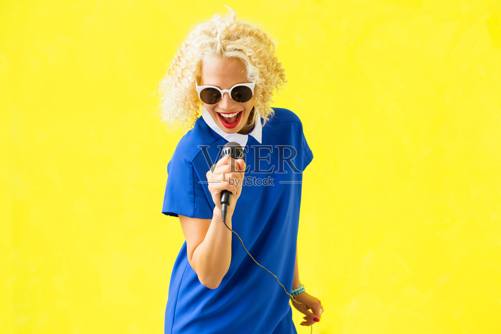 在麦克风里唱歌的时髦女人照片摄影图片
