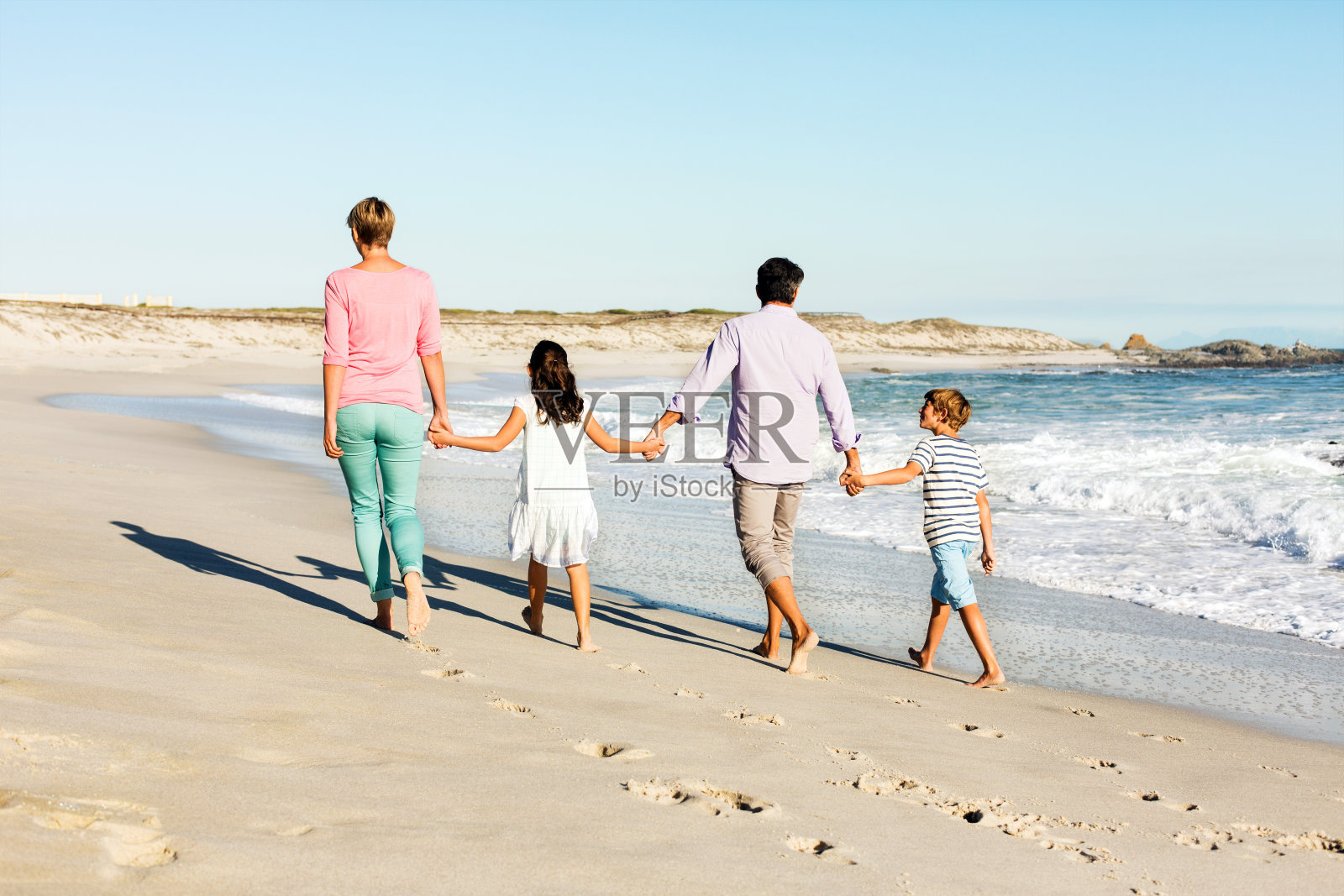 父母和孩子手牵着手在海滩上散步照片摄影图片