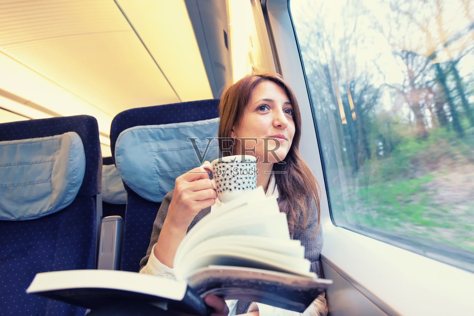 一个年轻的女人在跑着的火车里喝咖啡照片摄影图片
