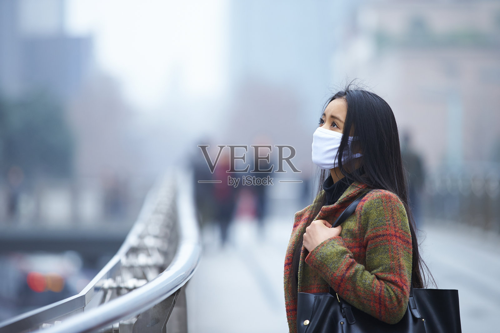 戴着面具的年轻女子在雾霾的城市里照片摄影图片