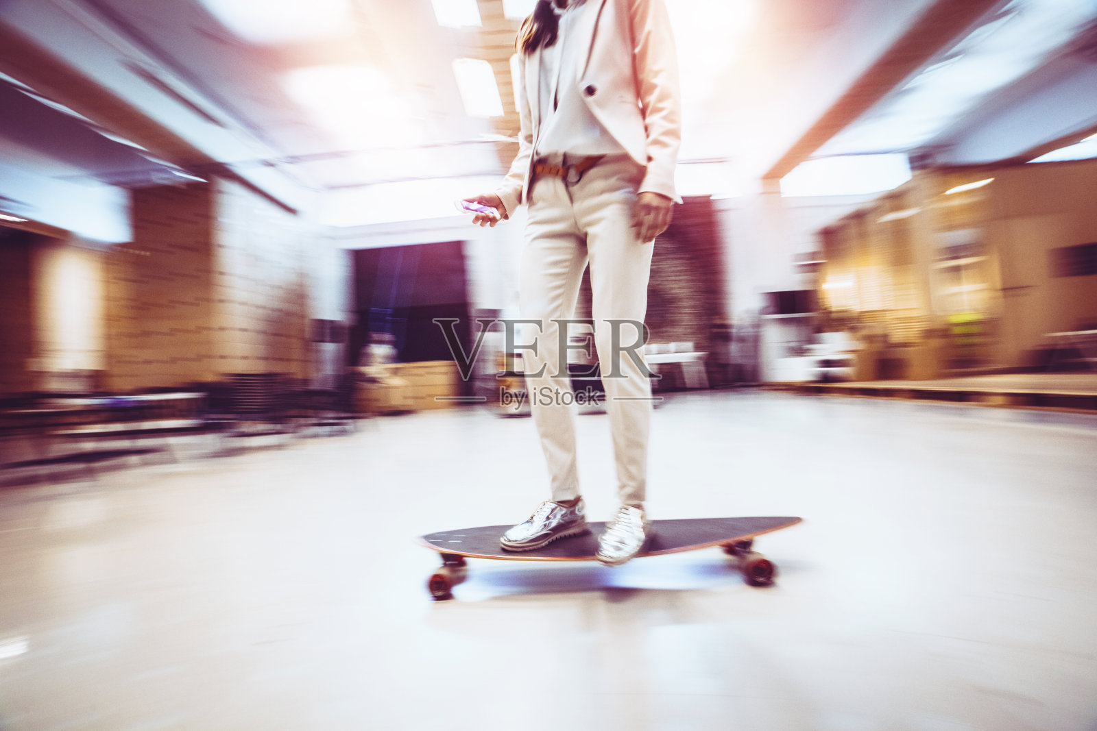Chic young businesswoman skateboarding in offices照片摄影图片