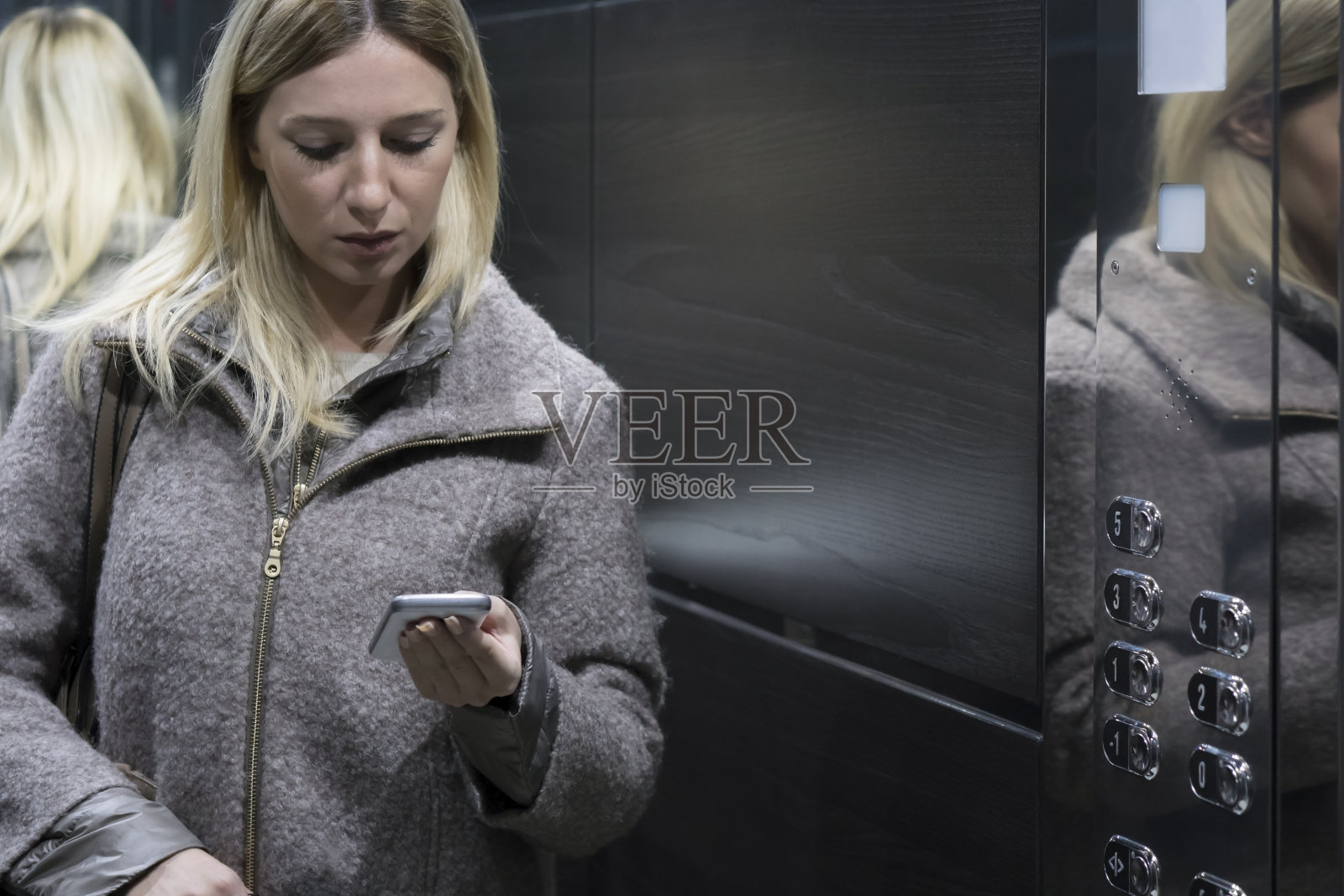 女商人在电梯里用智能手机照片摄影图片