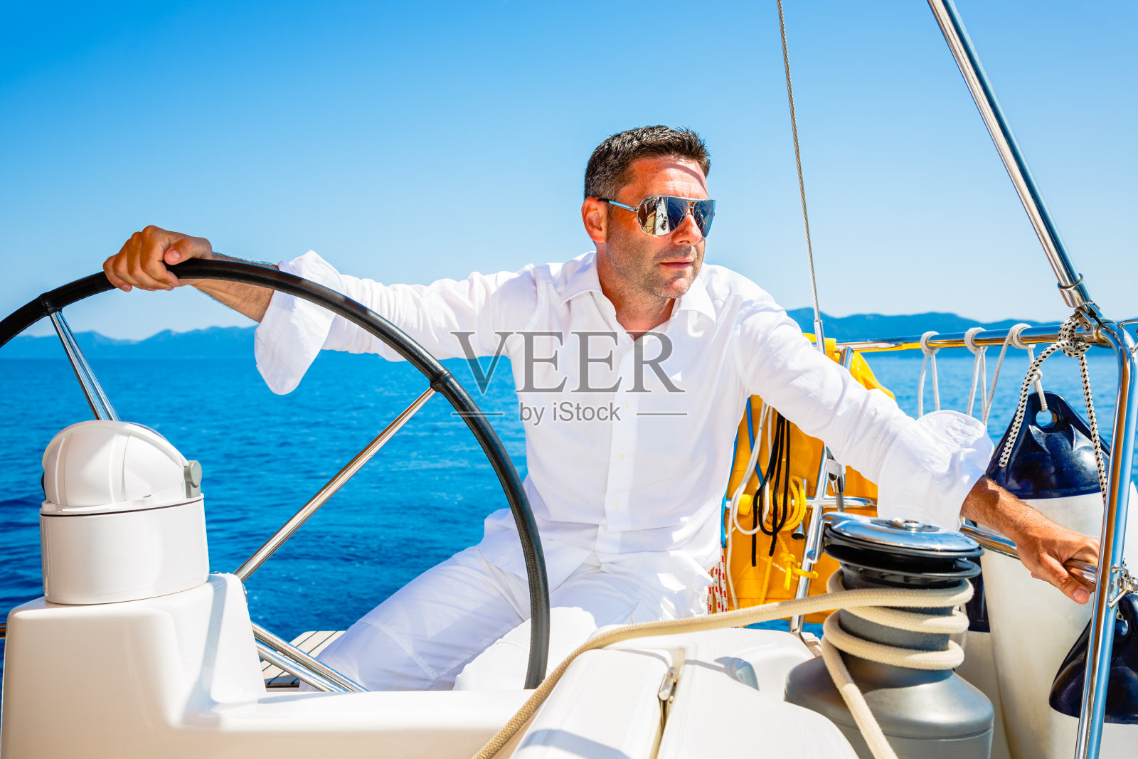 穿着白衣的男人驾着帆船航行照片摄影图片