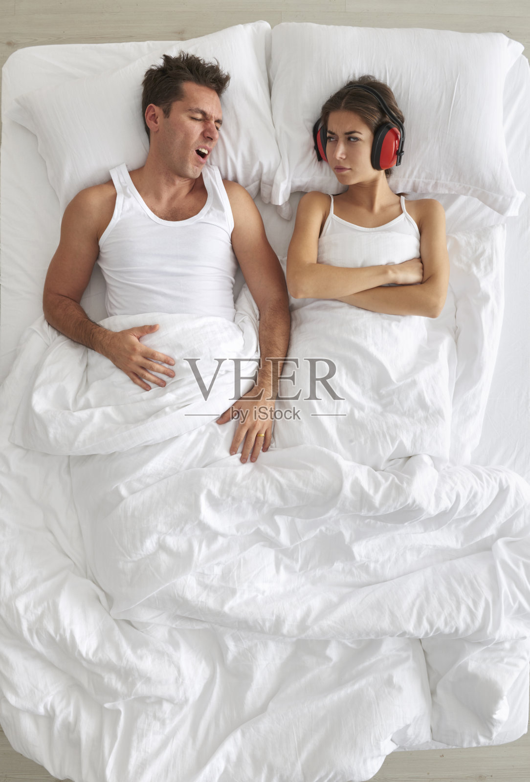 男人在床上打鼾，女人戴着护耳器照片摄影图片