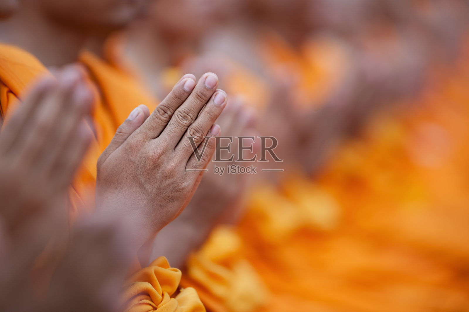 在泰国的一座佛寺里，泰国佛教僧侣正在瞻仰佛祖。选择性地聚焦在前景中的手。照片摄影图片