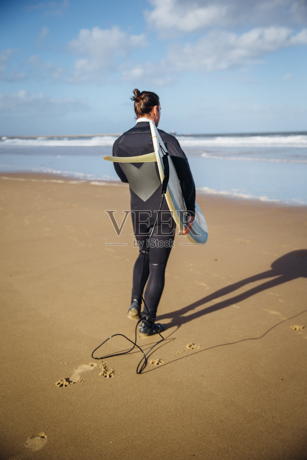 穿着潜水服拿着冲浪板的男人照片摄影图片