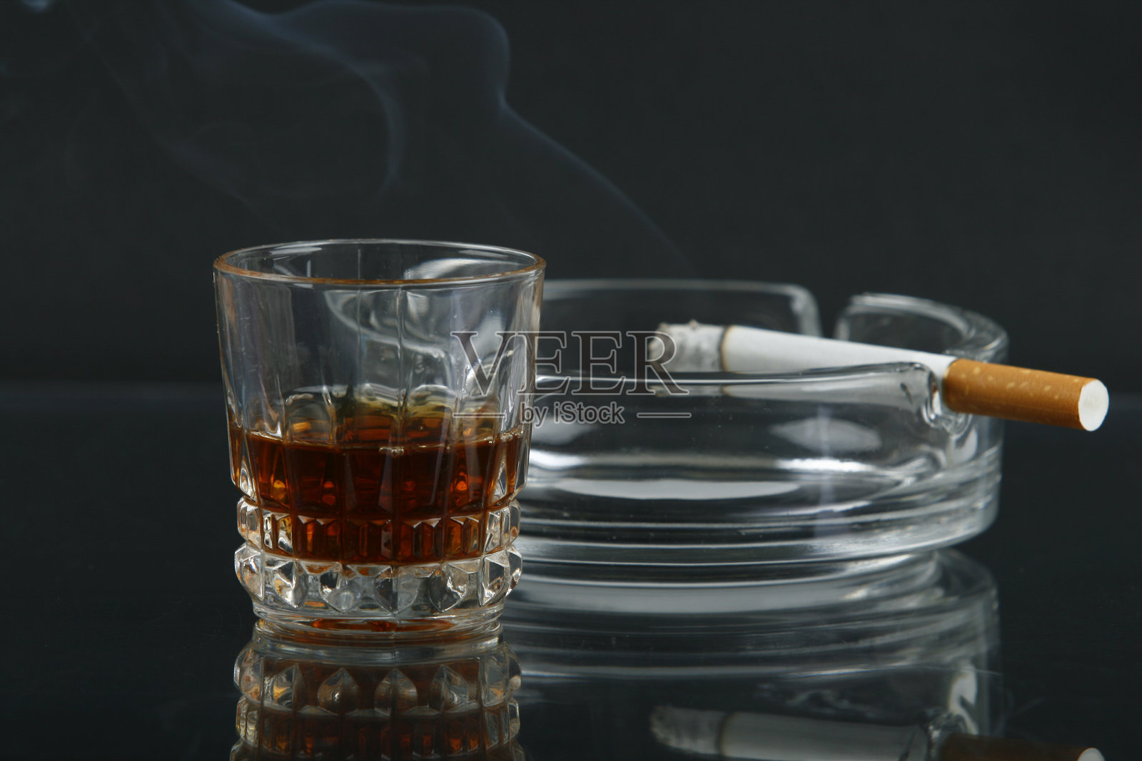 一杯威士忌，一根烟灰缸里的香烟照片摄影图片