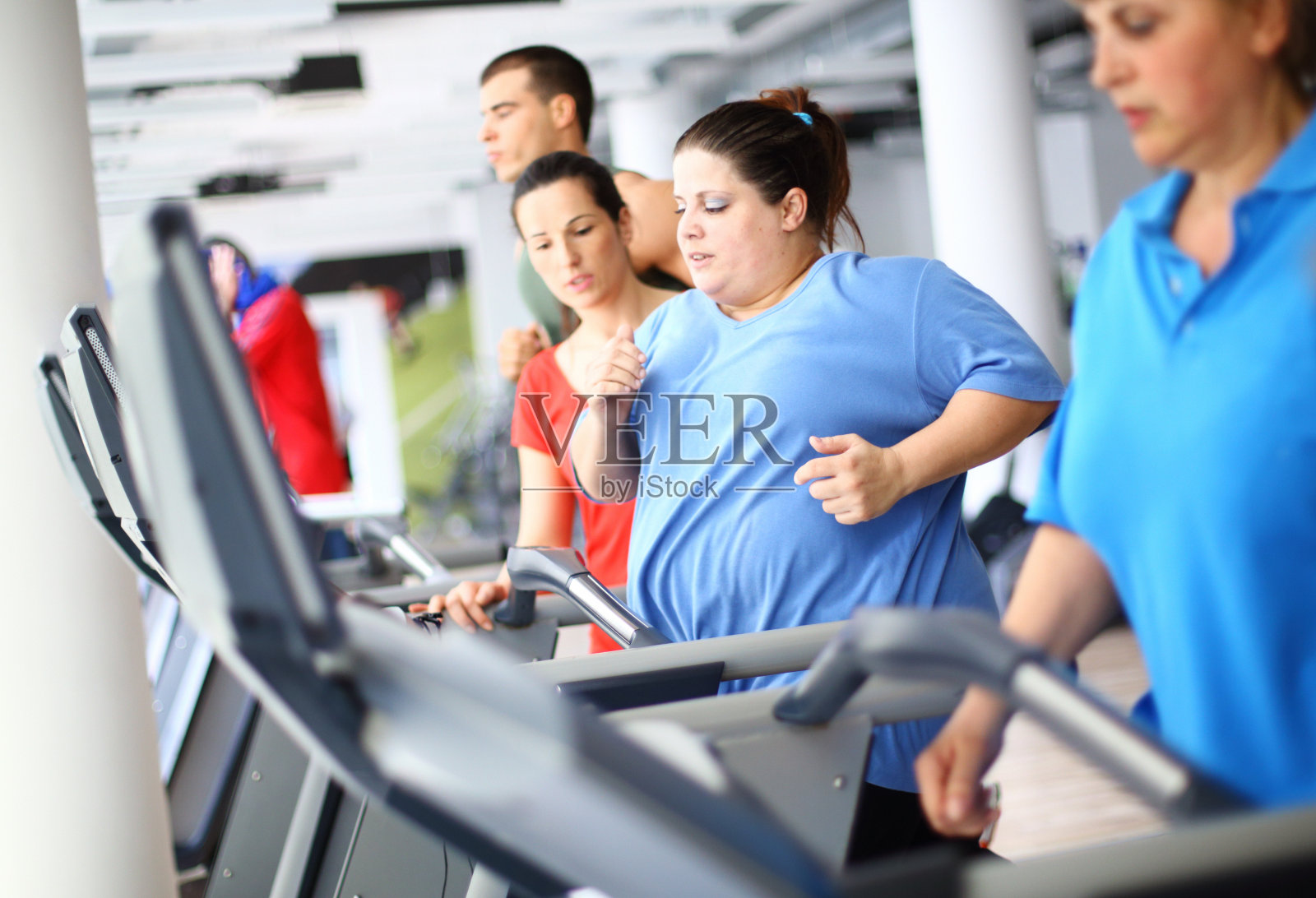 在跑步机上锻炼的超重女性。照片摄影图片