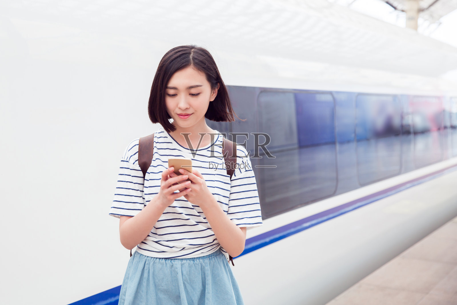 一名女子在火车站站台上用智能手机等待照片摄影图片