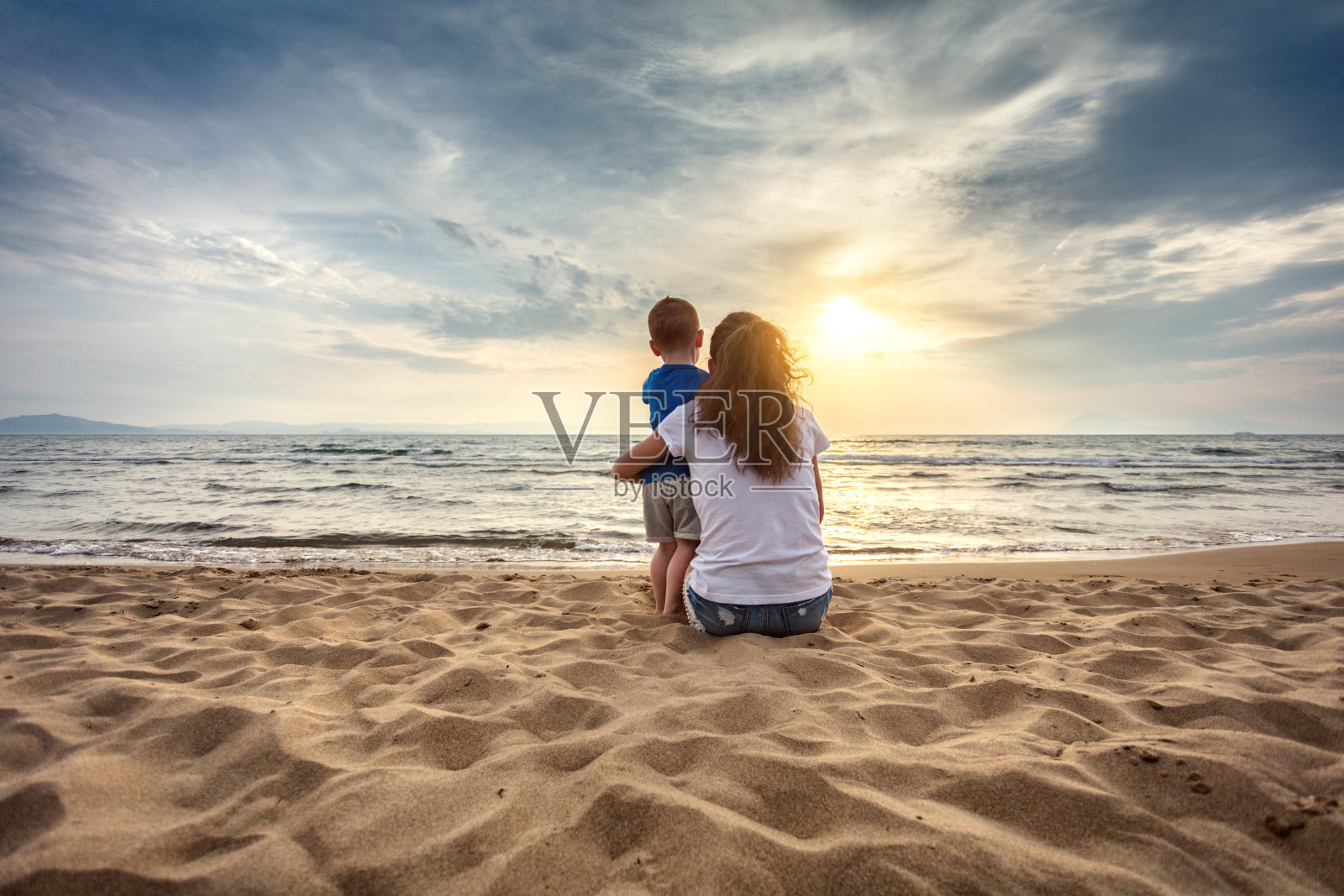 母亲和儿子在海滩上欣赏日落照片摄影图片