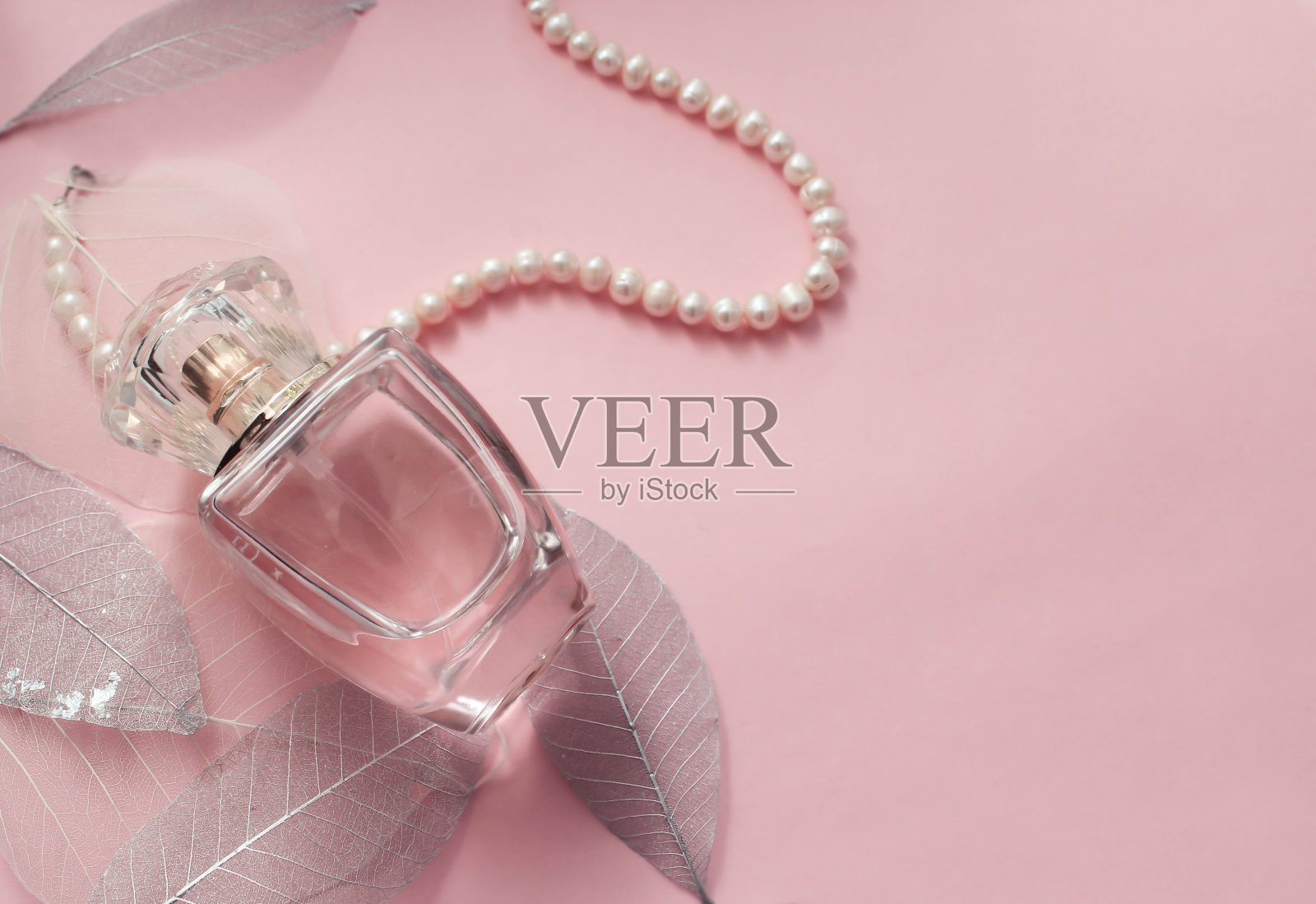 这款香水以粉红色为背景，带有装饰性的叶子照片摄影图片