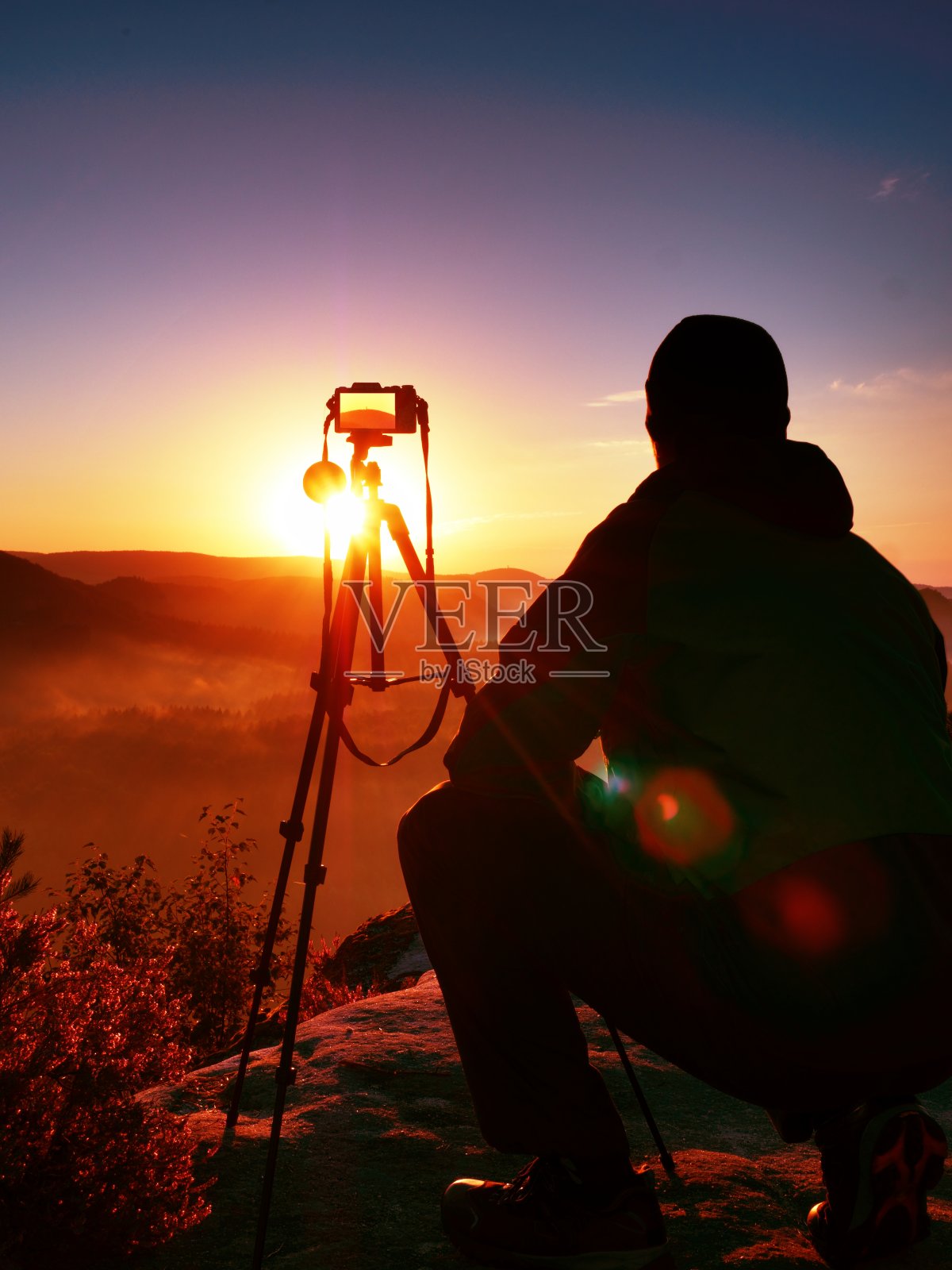 摄影师用相机在岩石的顶峰拍照照片摄影图片