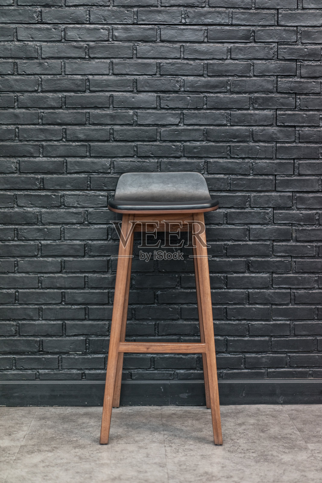 木材和皮革酒吧椅在黑色砖墙背景，室内概念正面视图照片摄影图片