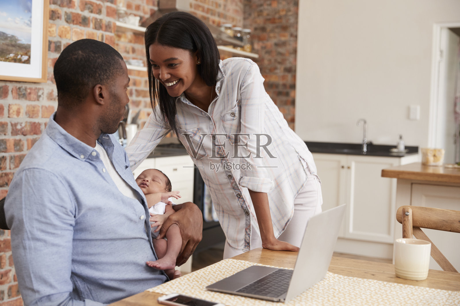 用笔记本电脑工作的父亲抱着刚出生的儿子和母亲照片摄影图片